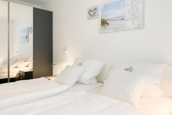 A hotel room with a bed, a mirror, and wall art. - Timmare IV Little Crab (Timmendorfer Strand)