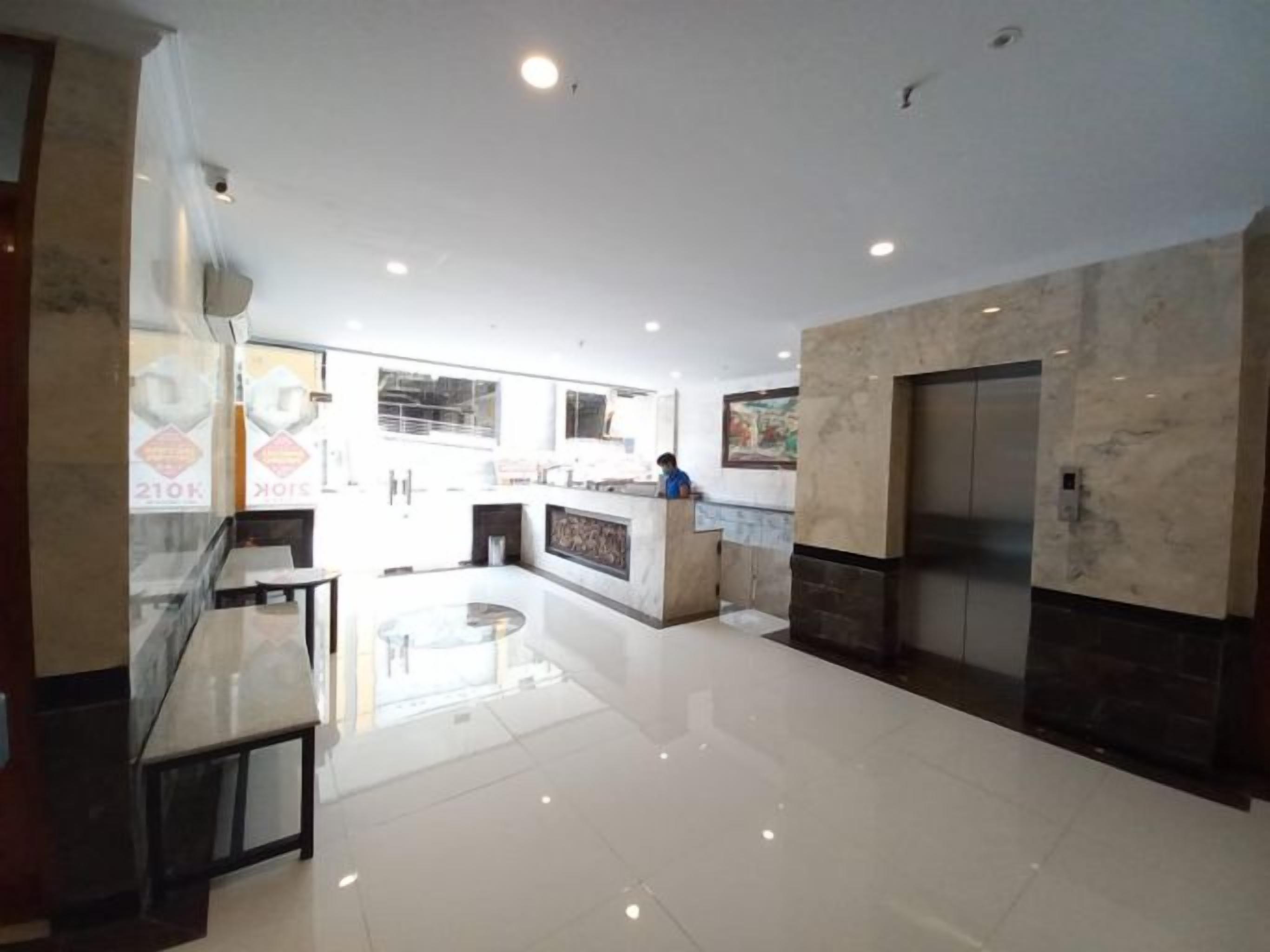 A spacious lobby with a central island, a reception desk, and an elevator.