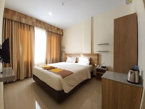A hotel room with a large bed, a bedside table, a desk, and a wardrobe. - Batam Harbour Hotel 2 (Batam)