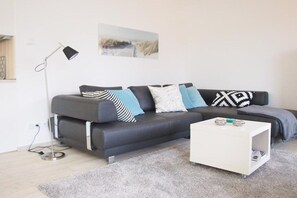 Ein modernes Wohnzimmer mit einem grauen Sofa, einem weißen Couchtisch und einer Stehlampe.