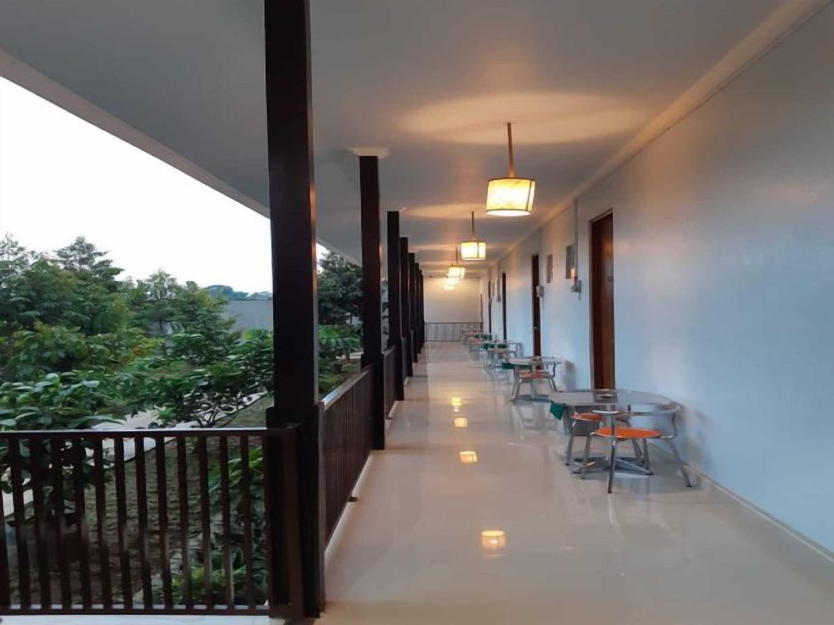 A corridor with a balcony, chairs, and hanging lights.