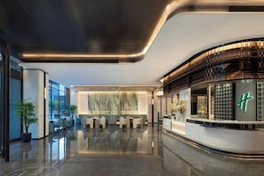 Un hall d’hôtel moderne avec un comptoir d’accueil, un espace salon et une grande fenêtre.