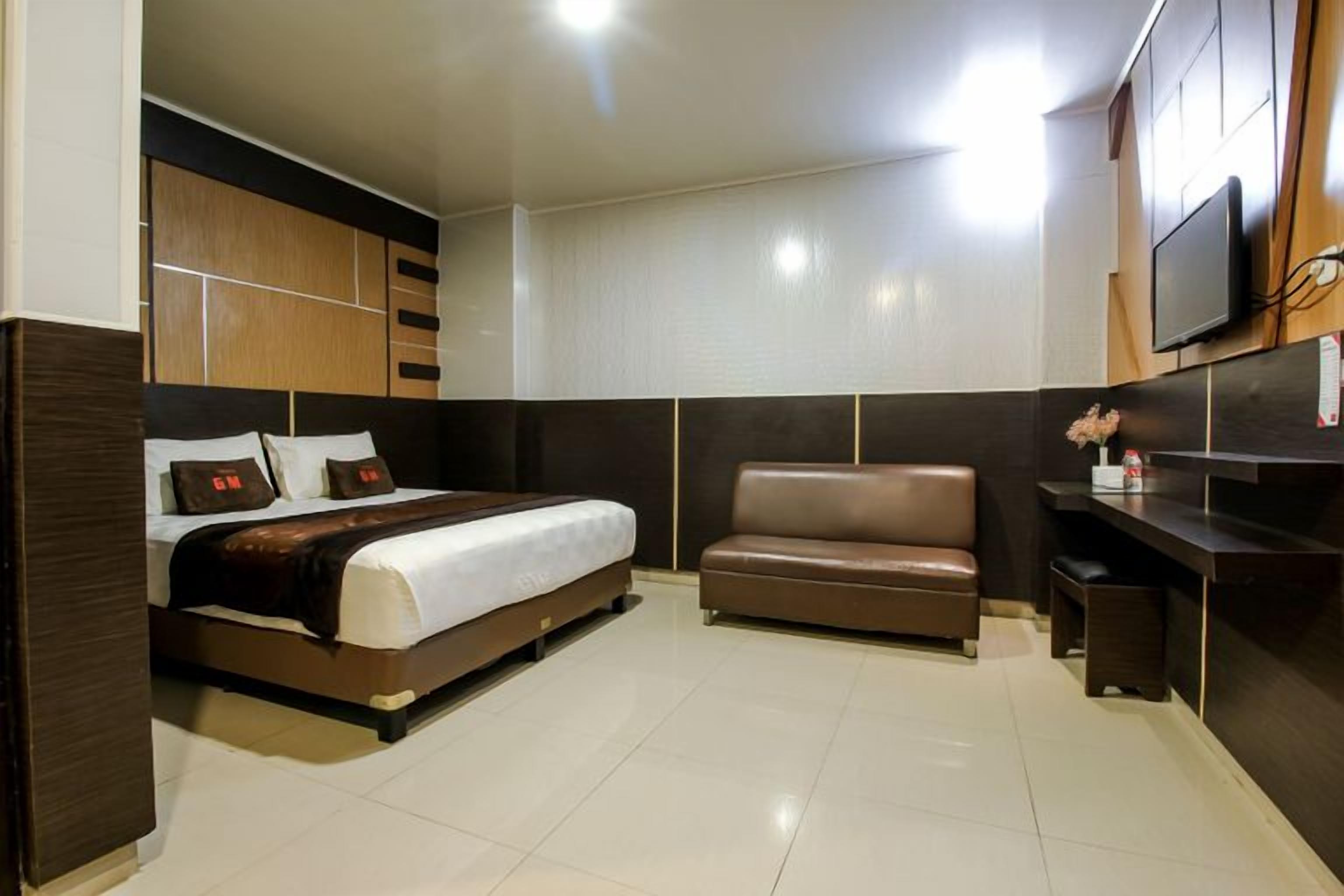 A hotel room with a bed, a sofa, a TV, and a desk.