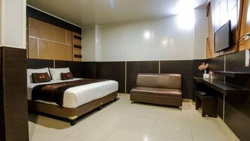 A hotel room with a bed, a sofa, a TV, and a desk.