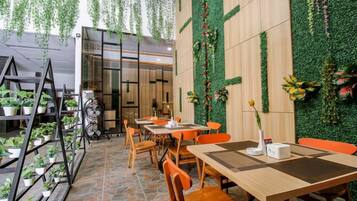 An indoor dining area with tables and chairs, a staircase, and hanging plants.