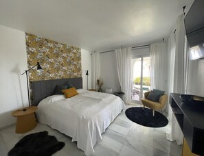 A modern bedroom with a large bed, a side table, a chair, and a television. - Holiday Apartment With 1 Bedroom (La Herradura-Marina Del Este Granada)