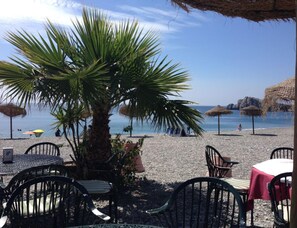 A beachside restaurant with outdoor seating, palm trees, and a view of the sea. - Holiday Apartment With 1 Bedroom (La Herradura-Marina Del Este Granada)