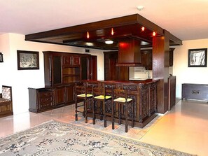 Una cocina con una isla central, taburetes de bar y un tapete decorativo.
