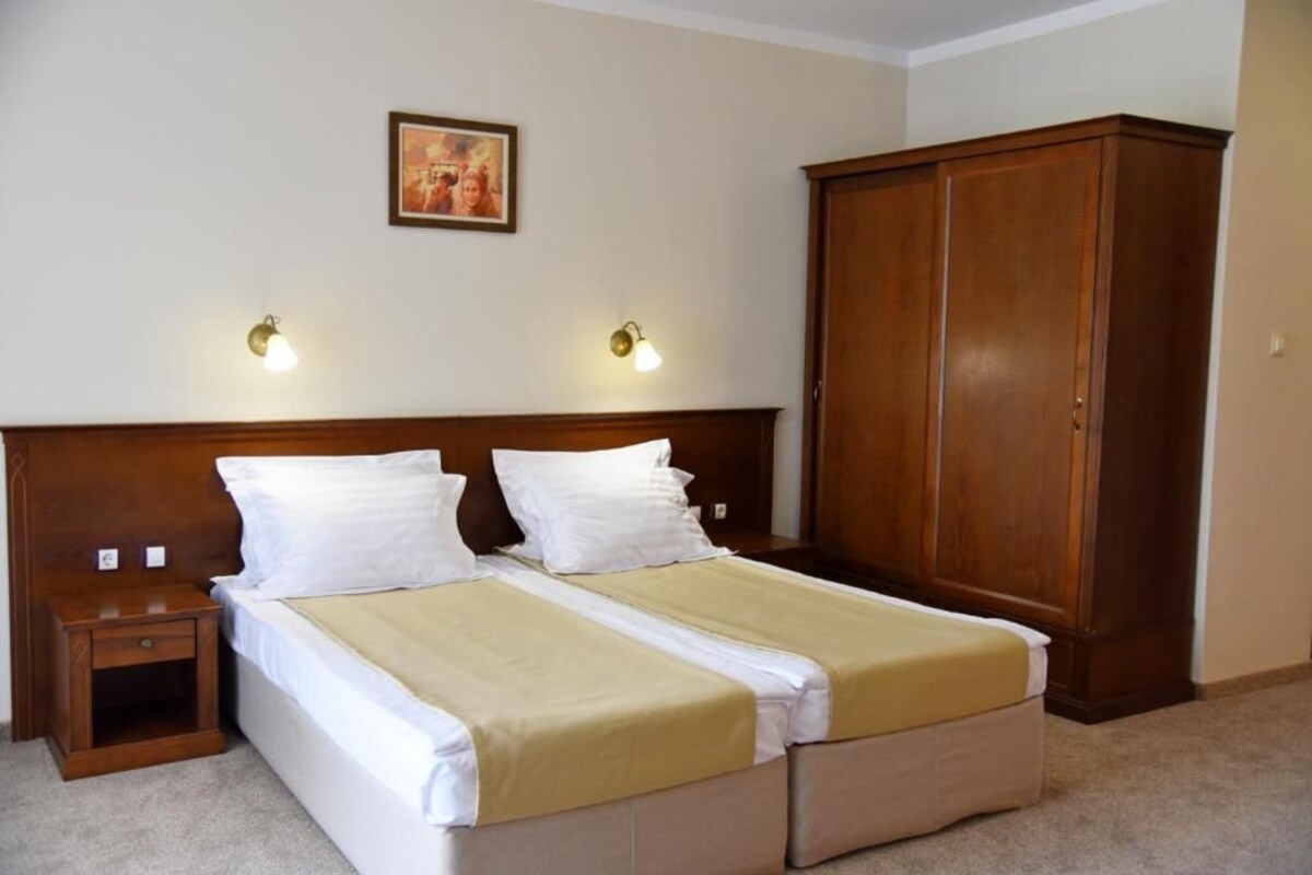 A double bed with a wooden headboard, two bedside tables, a wardrobe, and two wall-mounted lamps.
