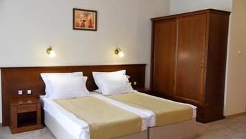 A double bed with a wooden headboard, two bedside tables, a wardrobe, and two wall-mounted lamps.