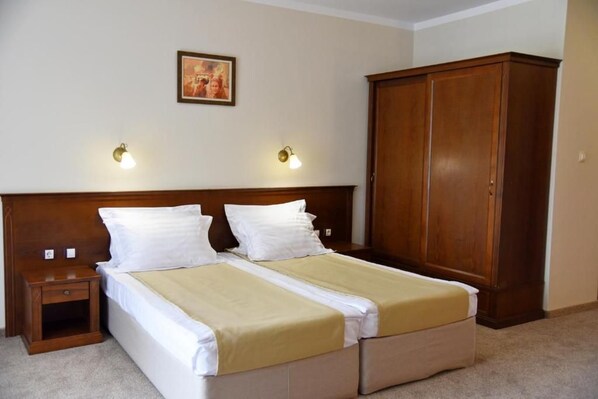 A double bed with a wooden headboard, two bedside tables, a wardrobe, and two wall-mounted lamps. - villa Maria Revas (Sunny Beach)