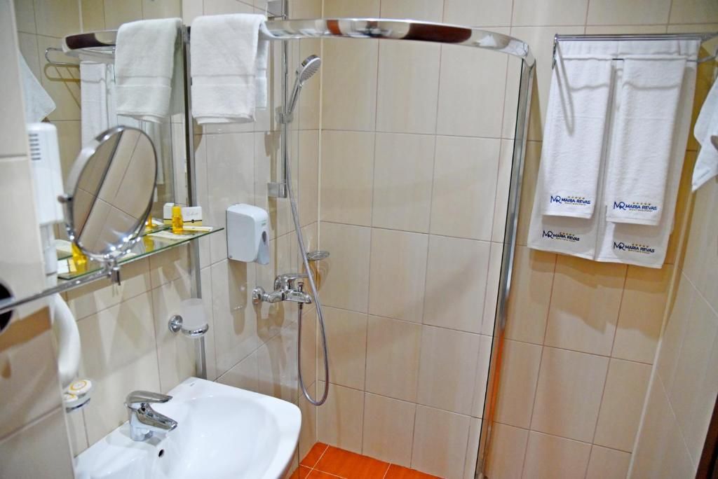 Un baño con lavamanos, espejo, ducha y toallero.