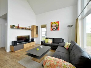 A modern living room with a flat-screen TV, a sofa, a coffee table, and a large window. - Holiday Home With 3 Bedrooms (Trent)