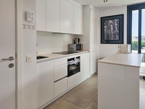 Eine moderne Küche mit weißen Schränken, einer eingebauten Mikrowelle und einer Kaffeemaschine.