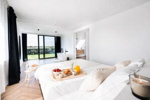 A modern hotel room with a large bed, breakfast tray, and a view of the outdoors. - Villa Awans – Luxury stay for 6 with Pool (Awans)