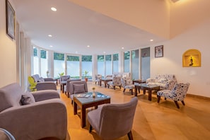 A spacious lounge area with multiple seating options, including sofas and armchairs, arranged around a central coffee table.
