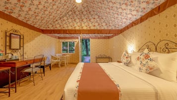 A bedroom with a bed, a desk, and a chair. There is a window and a door leading to an outdoor area.