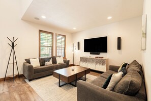 A modern living room with a sofa set, a coffee table, a TV, and a bookshelf. - 5BR, 4.5BA Park City retreat near Jordanelle, sleeps 18. (Hideout)