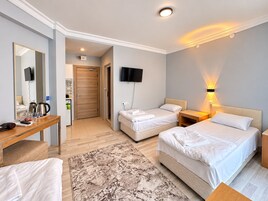 Habitación de hotel con cama, mesitas de noche, escritorio, espejo, televisión y una lámpara de pared.