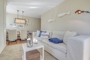 A living room with a white sofa, a coffee table, and a dining area with chairs and a table. - The “large artists’ community,” with excellent access to the West Beach in Wenningstedt (Wenningstedt-Braderup (Sylt))