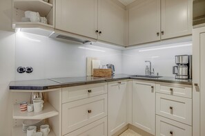 Een moderne keuken met witte kasten, een granieten aanrechtblad en roestvrijstalen apparatuur.