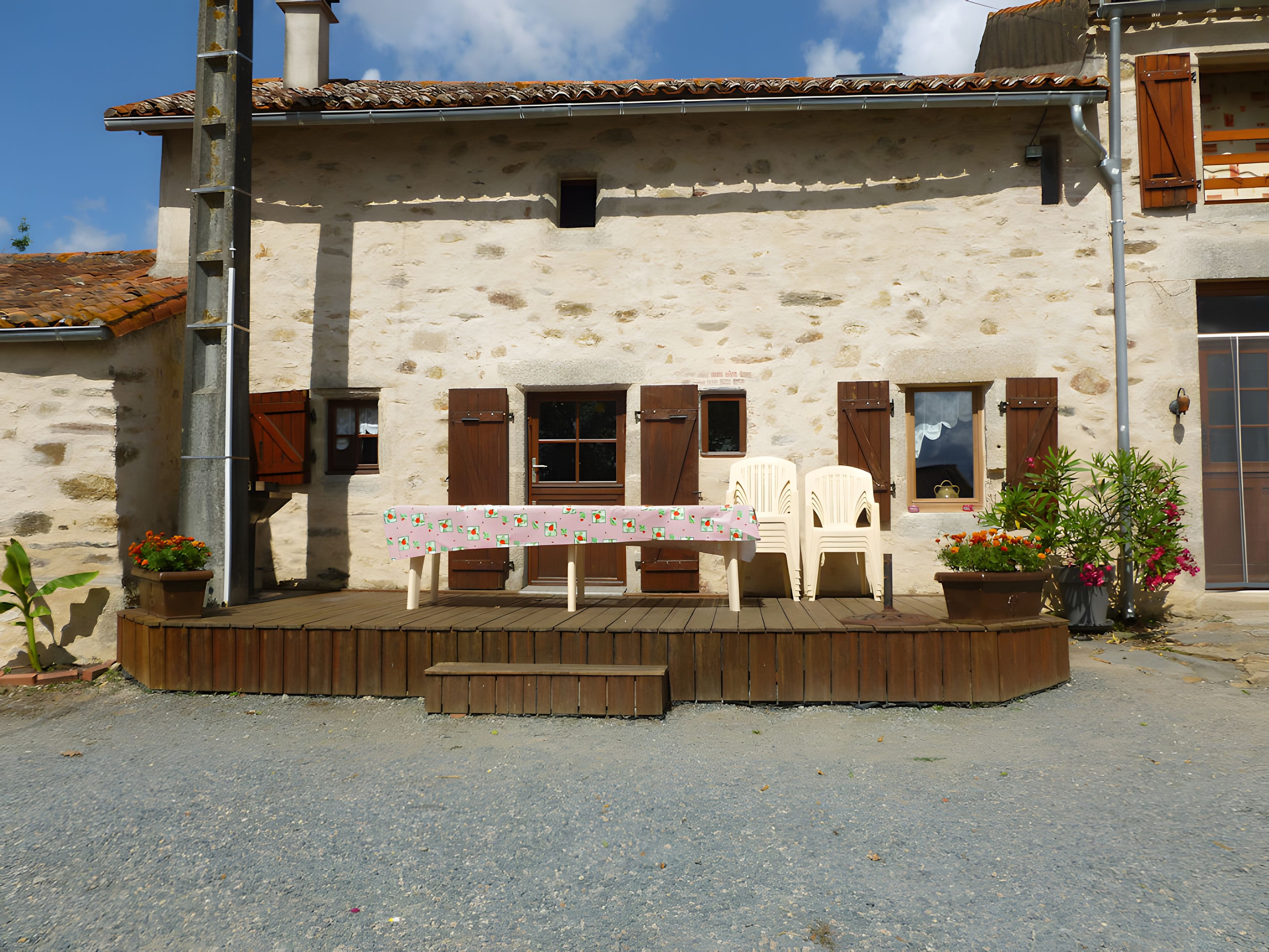 A rustic building with a balcony, outdoor seating, and potted plants.