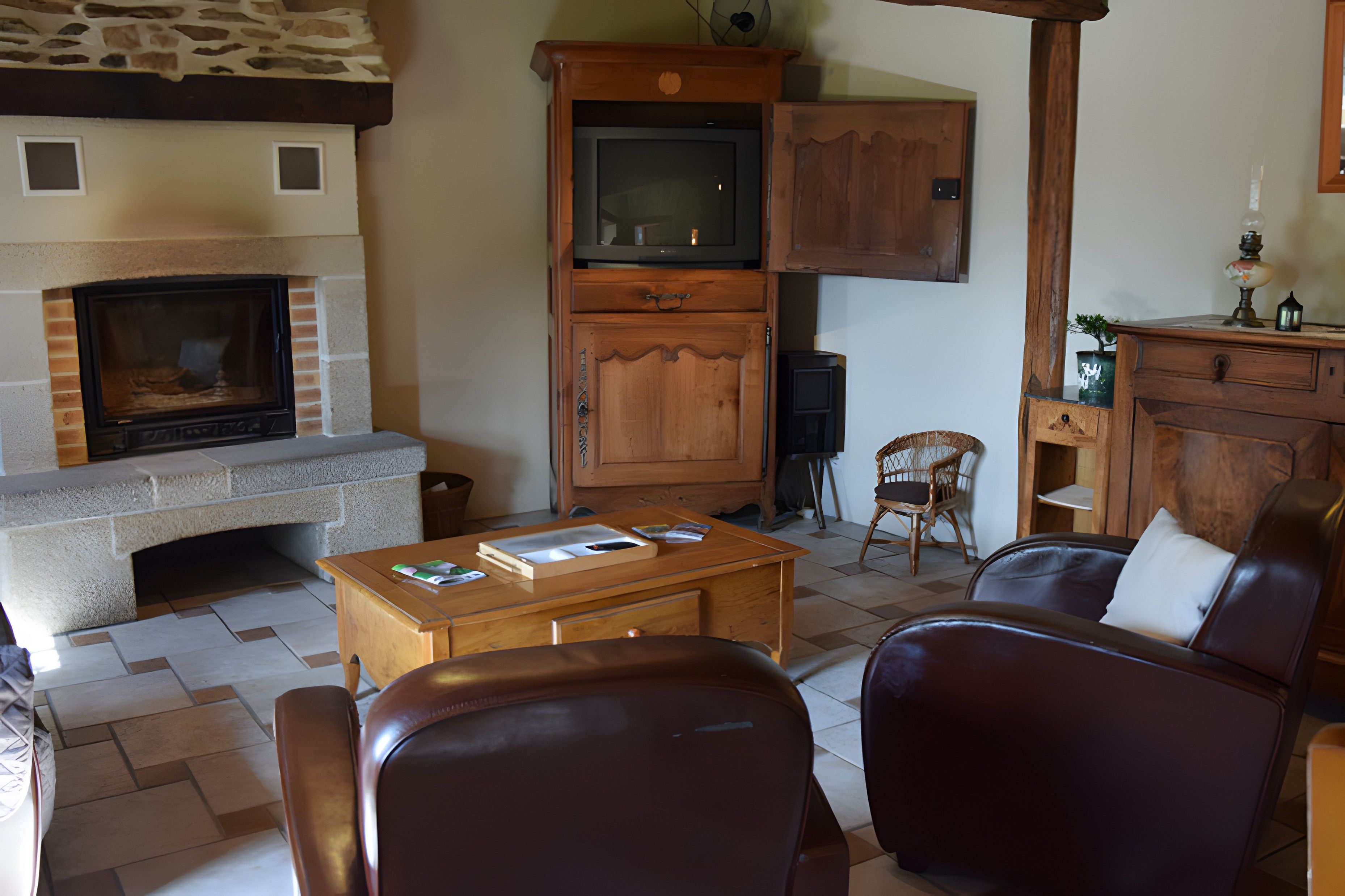 A living room with a stone fireplace, wooden cabinets, a television, and leather furniture.