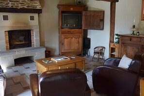 Een woonkamer met een stenen open haard, houten kasten, een televisie en lederen meubels.