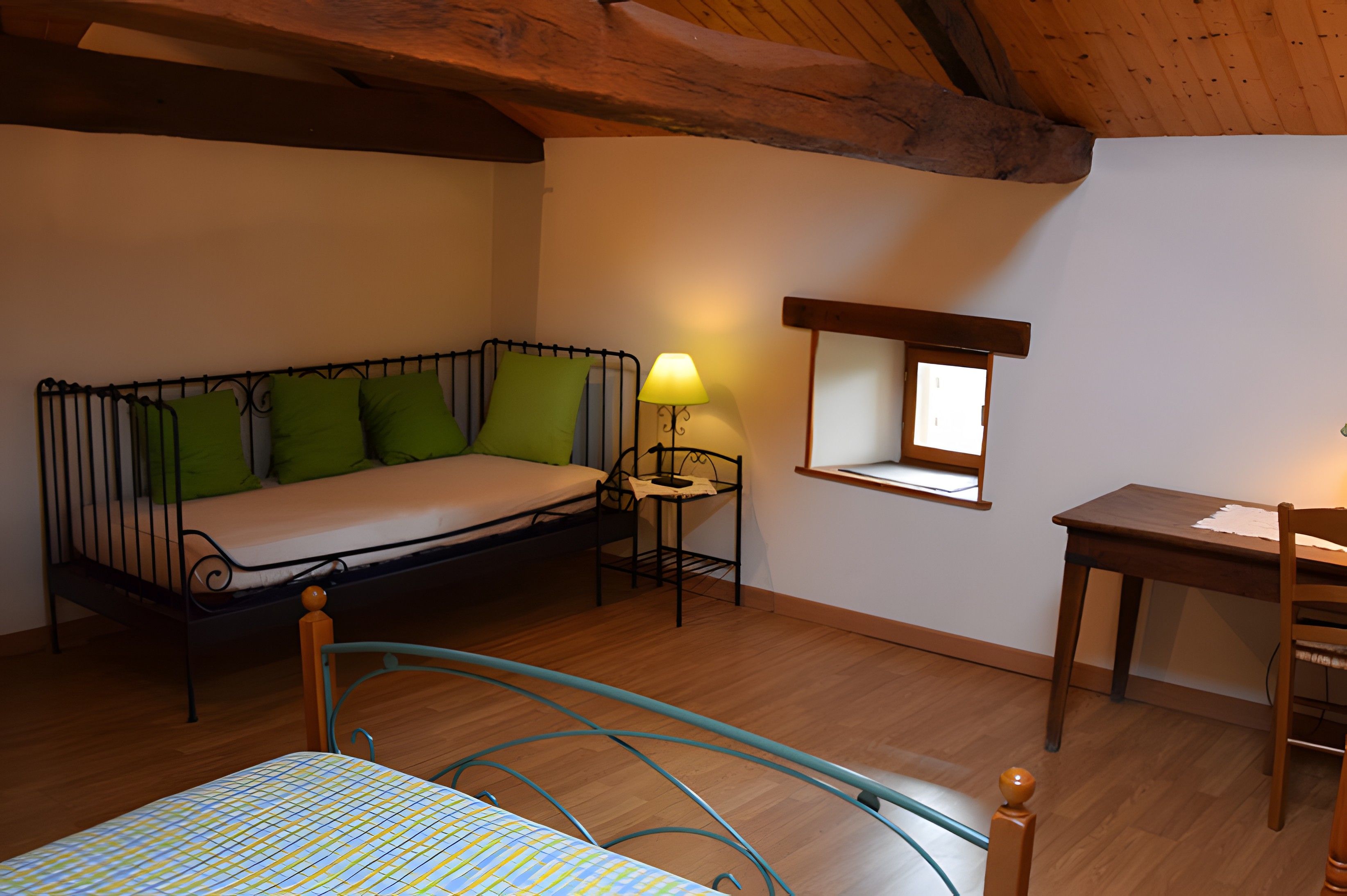 Quarto pequeno e aconchegante com cama, escrivaninha e janela.