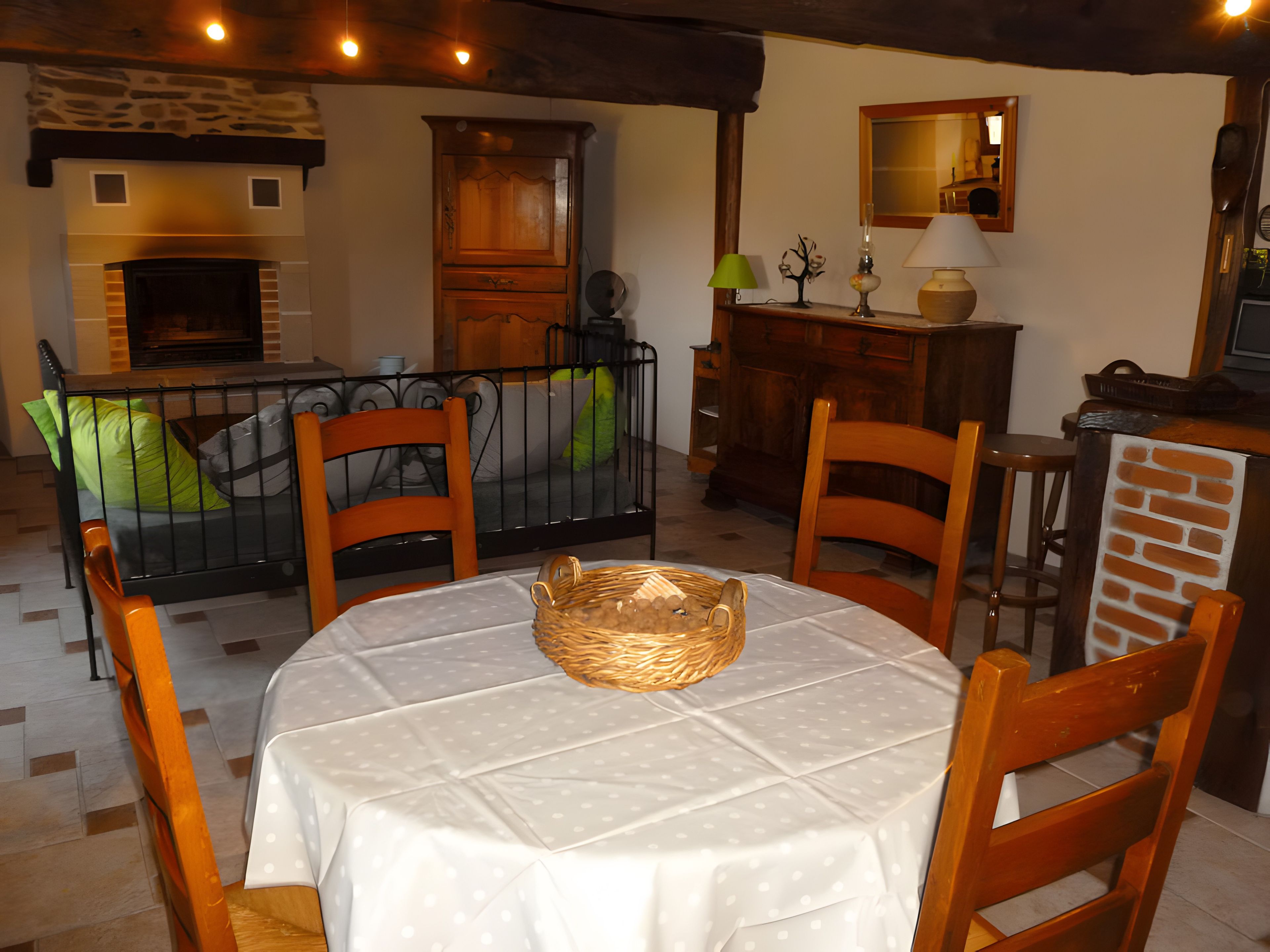 Een eethoek met een ronde tafel, stoelen, een rieten mand en een open haard.