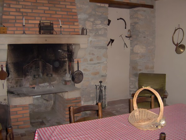 Een landelijke keuken met een bakoven, hangend keukengerei en een geruit tafelkleed.