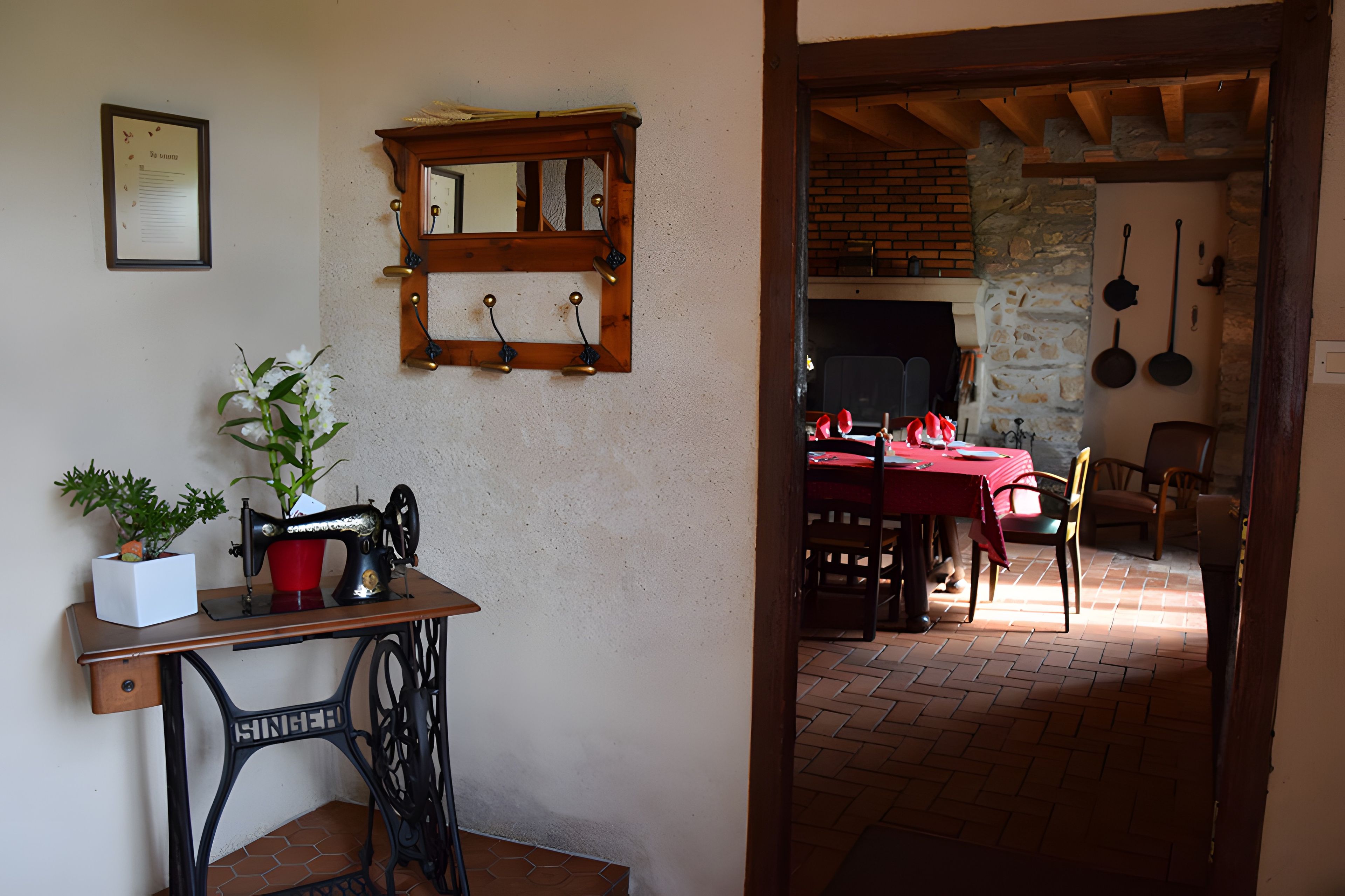 A rustic interior with a sewing machine, a mirror, and a dining area with a brick fireplace.