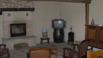 Uma sala de estar com lareira, televisão sobre um móvel e mobiliário de madeira.