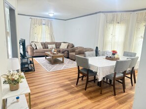 A living room with a sofa, coffee table, dining table with chairs, and a TV. - 3-bedroom house in peaceful Niagara Falls with AC comfort (Niagara Falls)