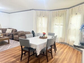 A dining area with a table set for four, surrounded by grey upholstered chairs. - 3-bedroom house in peaceful Niagara Falls with AC comfort (Niagara Falls)