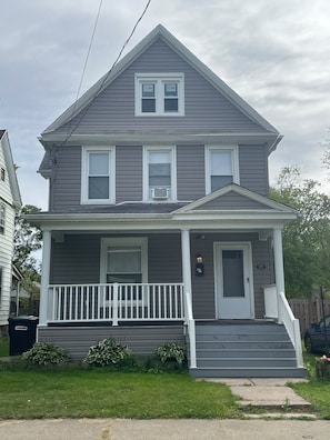A two-story house with a front porch, a door, and a mailbox. - 3-bedroom house in peaceful Niagara Falls with AC comfort (Niagara Falls)