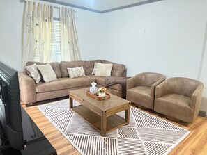 A living room with a brown sofa, a wooden coffee table, and a patterned rug. - 3-bedroom house in peaceful Niagara Falls with AC comfort (Niagara Falls)