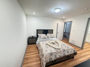 A bedroom with a bed, bedside tables, a lamp, and a door leading to another room. - 3-bedroom house in peaceful Niagara Falls with AC comfort (Niagara Falls)