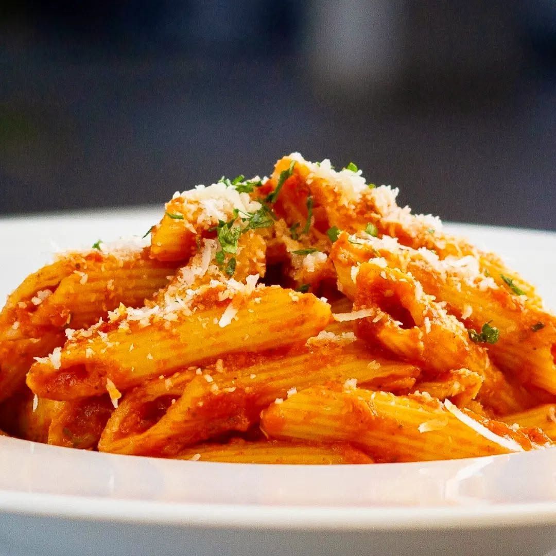 Eine Pasta-Käseplatte mit roter Soße, garniert mit geriebenem Käse und Kräutern.