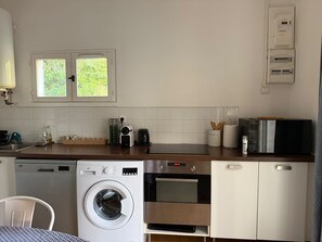 Eine kompakte Küche mit Waschmaschine, Mikrowelle und Kaffeemaschine.