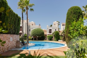 A swimming pool surrounded by greenery and buildings with Mediterranean architecture. - La Manga Club Las Brisas Townhouse 370 (Murcia)
