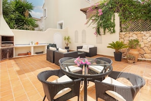 An outdoor patio with wicker furniture, a glass table, and potted plants. - La Manga Club Las Brisas Townhouse 370 (Murcia)