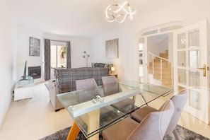 Un salon moderne avec une table basse en verre, un canapé, une cheminée et un escalier menant à un autre niveau.