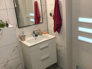 A bathroom with a white sink, a mirror, and a marble-patterned wall. - Holiday Apartment With 1 Bedroom (Szklarska Poreba)