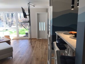 A modern kitchen with a wooden countertop, a built-in oven, and a dining area with a white chair. - Holiday Apartment With 1 Bedroom (Szklarska Poreba)