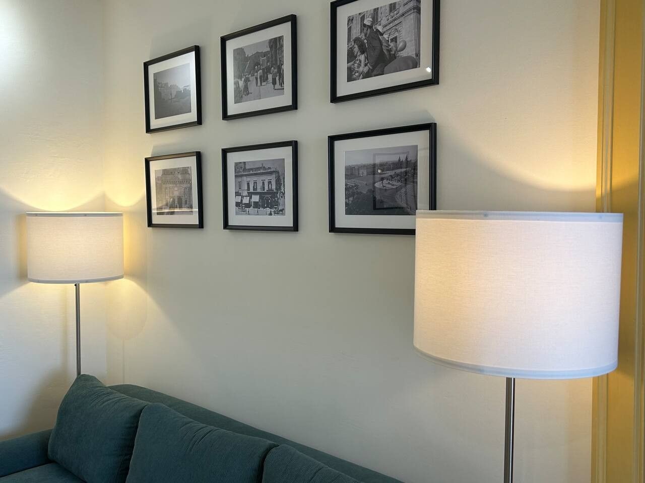 A room with a sofa, a lamp, and six framed pictures on the wall.