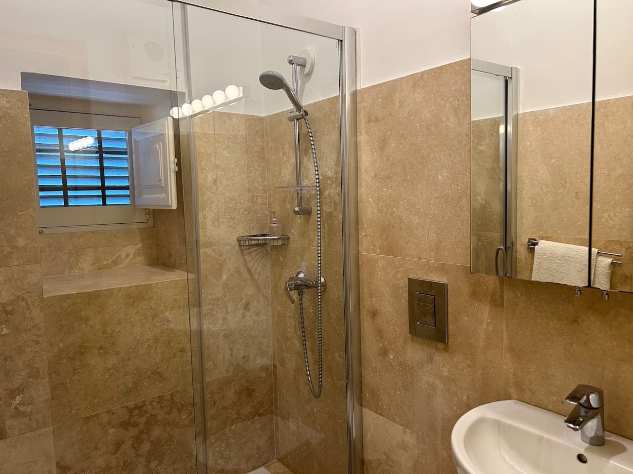 A modern bathroom with a glass-enclosed shower, a sink, and a mirror.