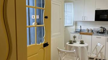 A compact kitchen with white cabinets, a black oven, and a small dining table with chairs.