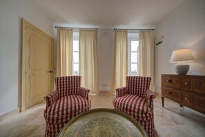 A room with two checkered armchairs, a wooden cabinet with a lamp, and a patterned table. - Penthouse w/ unique harbour view (Il-Belt Valletta)