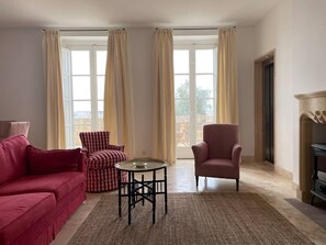 A living room with a red sofa, a striped armchair, a round table, and a fireplace. - Penthouse w/ unique harbour view (Il-Belt Valletta)